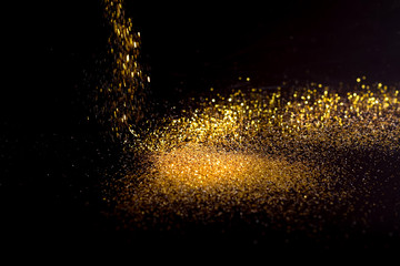 Sprinkle gold dust on a black background with copy space