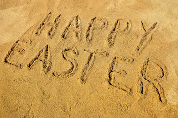 Message Happy Easter handwritten on the golden sandy beach