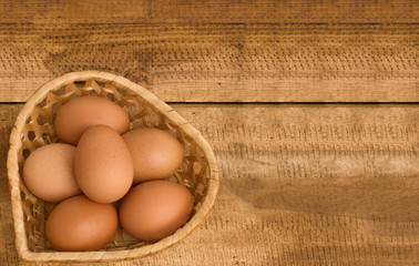 Easter eggs in wicker basket  on wooden vintage background. Top view, copy space.