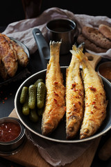 Fried smelt on a dark pan with sauce
