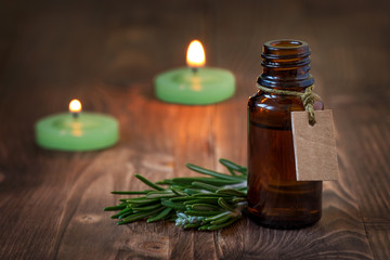 Rosemary essential oil in glass bottle on wooden background