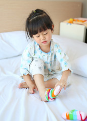 Lovely little asian girl trying to put a socks on the bed.