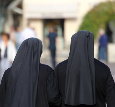 two sisters with long blacks clothes they walk through the stree
