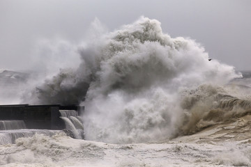 Big stormy wave breaking over pier