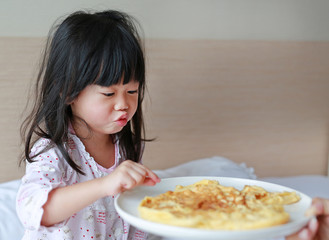 Little child girl looking Healthy breakfast with egg omelet on the bed.