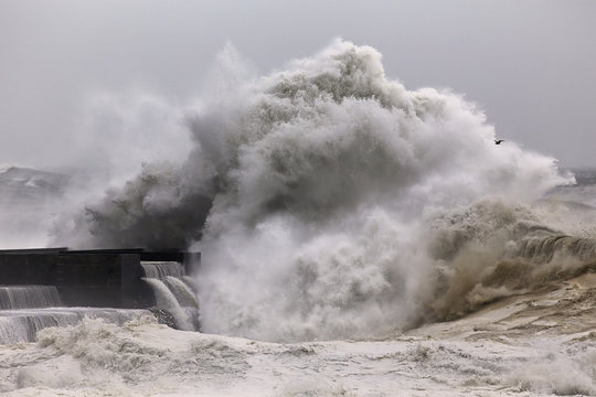 Big stormy wave breaking over pier