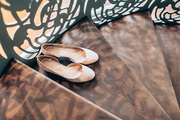 Peach women's wedding shoes on wooden stairs with derative railings
