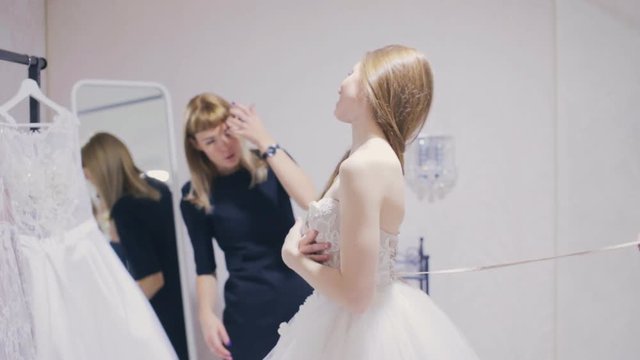 Pretty woman chooses a wedding dress in bridal shop
