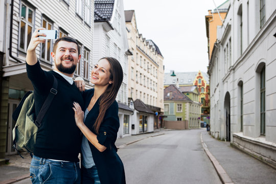 Young couple doing selfie by phone on the street of european city.