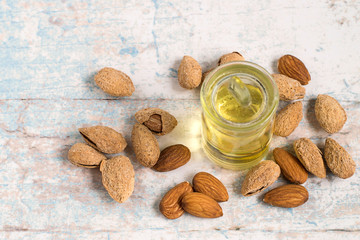 Almond oil.   Almond oil in a glass bottle and almond nuts on a light wooden background.