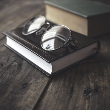 Old vintage books and glasses on a wooden table