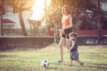 Young mother with daughter playing soccer