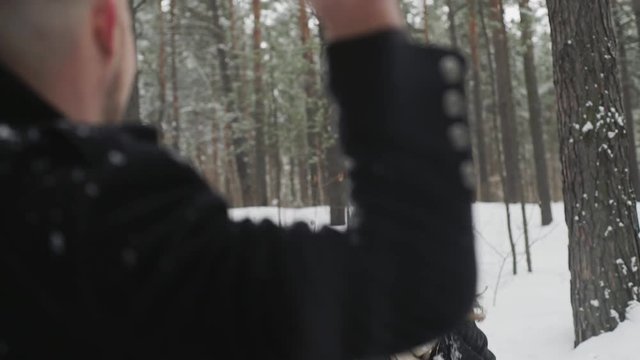 Man and woman couple is throwing snowballs to each other together in a snow winter forest