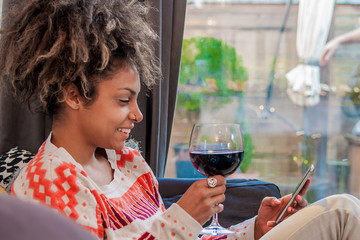 Young hipster girl using modern smartphone device while sitting at home and communicate with friends in social networks,female freelancer working from home, happiness and enjoyment lifestyle