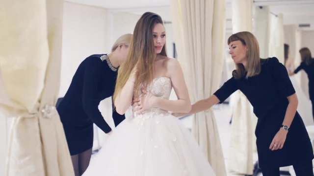 Pretty woman trying on wedding dress in fitting room