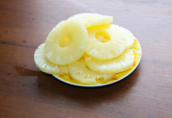 Canned pineapple on a plate on wooden table