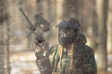 girl playing paintball in overalls with a gun.