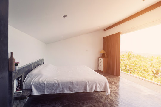 Bed room minimalism interior with cement floor, big open balcony and design elements