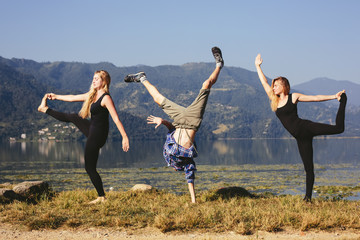 Happy funny yoga people try to doing fitness yoga exercises outdoor on beautiful mountain lake in Nepal