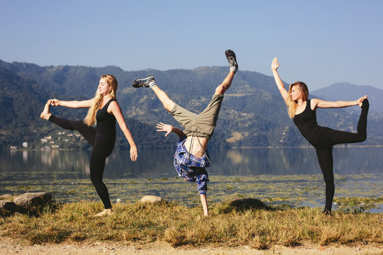 Happy funny yoga people try to doing fitness yoga exercises outdoor on beautiful mountain lake in Nepal