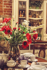 Kitchen room interior decorated with spring red flowers in vase on the table