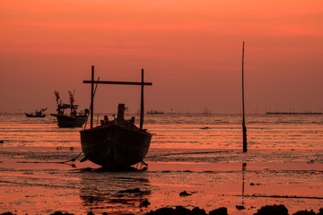Silhouettes of fishing boat with sunset sky background