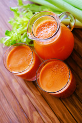 Fresh carrot juice poured into glasses and green celery