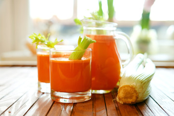 Fresh carrot juice poured into glasses and green celery