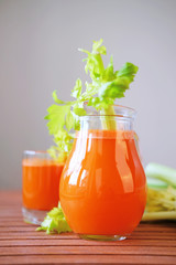 Fresh carrot juice poured into glasses and green celery