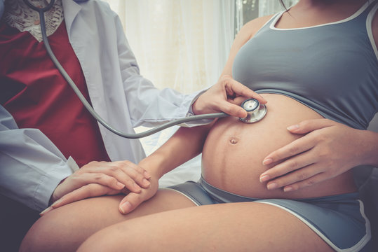 doctor using stethoscope examining pregnant woman