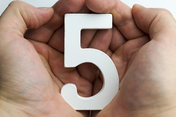 Hand holding number five.