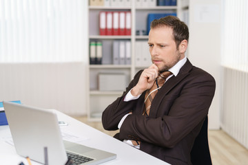 manager schaut mit ernstem gesicht auf sein notebook