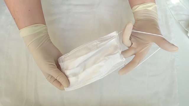 Hands in gloves hold a medical mask. Protection against viruses and infection. Medical practice.