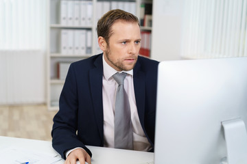 mann im büro schaut konzentriert auf den pc