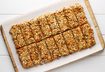 Homemade no bake granola bars with oat flakes, honey, dried apricots and seeds on white baking paper. - 139101894