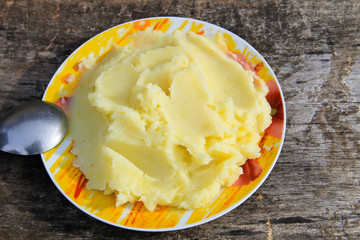 Mashed potatoes in a plate on rustic wooden table