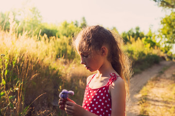 Cute little girl  with flowers on the meadow in summer day