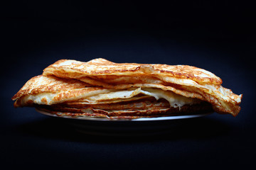 Russian pancakes on a plate against dark background
