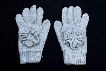 Pair of handmade wool knitted gloves on black background