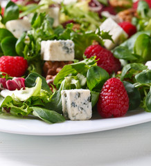 Green spring salad with blue cheese , raspberry and nuts