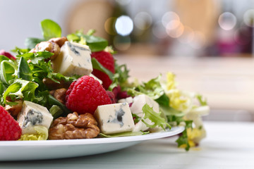 Green spring salad with blue cheese , raspberry and nuts