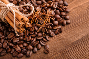 Coffee beans and cinnamon on a background of burlap. Roasted coffee beans background close up. Coffee beans pile from top with copy space for text. Seasoning. Spice. Cinnamon. Badian. Coffee house.