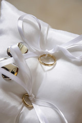 Anelli nuziali d'oro legati su un cuscinetto bianco