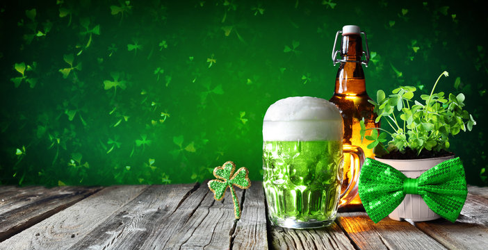 St Patrick's Day - Green Beer In Glass With Bottle And Clovers On Wooden Table
