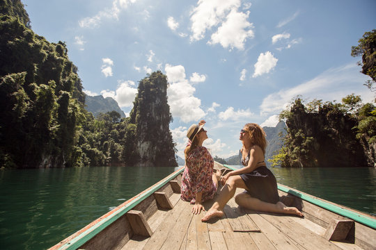 Yang girls traveling by boat exploring epic limestone cliffs in huge lake in Khao Sok National Park, Chiew lan lake, Thailand