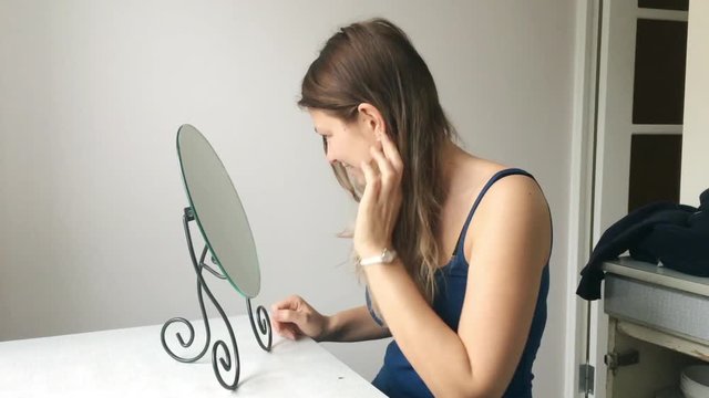 Portrait of a beautiful young woman with blonde hair looks in the mirror