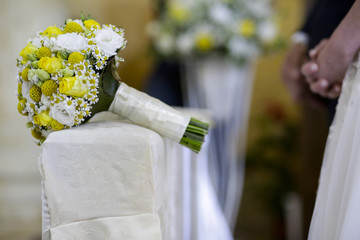bel Bouquet bianco e giallo appoggiato sul banchetto degli sposi durante la celebrazione del rito...