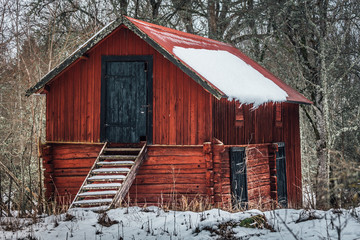 Old wooden barn in faded red color, standing in the forest in Sweden