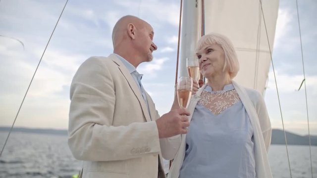 Happy senior couple toasting and drinking champagne on drifting yacht