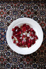 Piatto bianco con petali colorati sopra tappeto fantasia